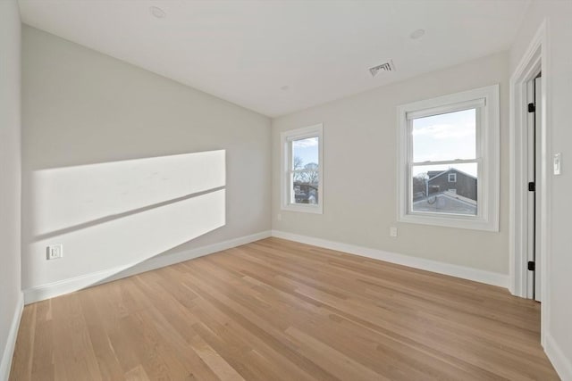 unfurnished room with baseboards, visible vents, and light wood finished floors