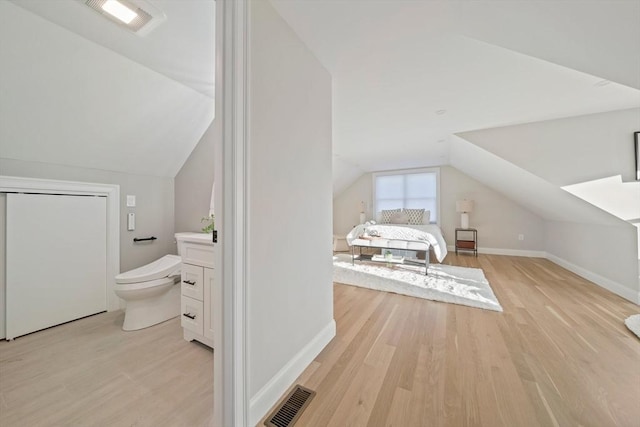 interior space featuring lofted ceiling, visible vents, toilet, wood finished floors, and baseboards