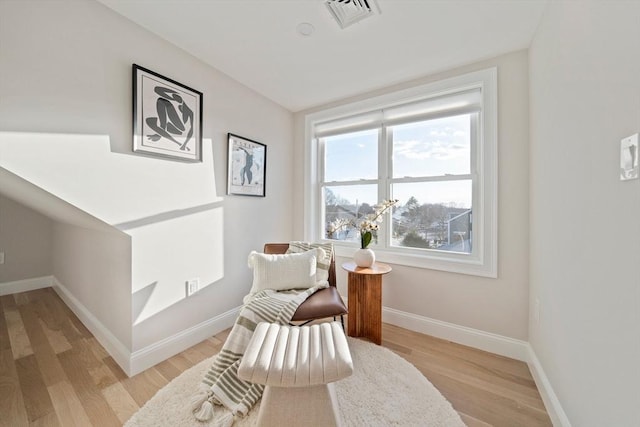 sitting room featuring light wood-style flooring, visible vents, and baseboards