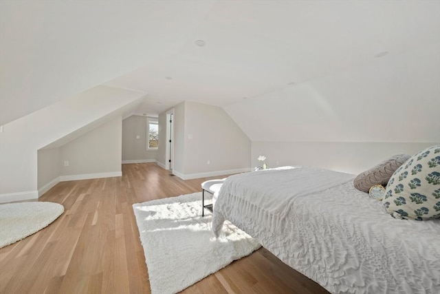 bedroom with vaulted ceiling, baseboards, and wood finished floors