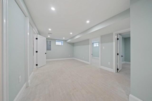 basement featuring light wood-type flooring, recessed lighting, electric panel, and baseboards