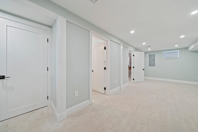 finished below grade area with light wood-style flooring, electric panel, baseboards, and recessed lighting