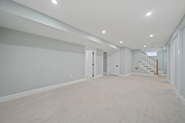 basement with light wood-type flooring, baseboards, stairway, and recessed lighting