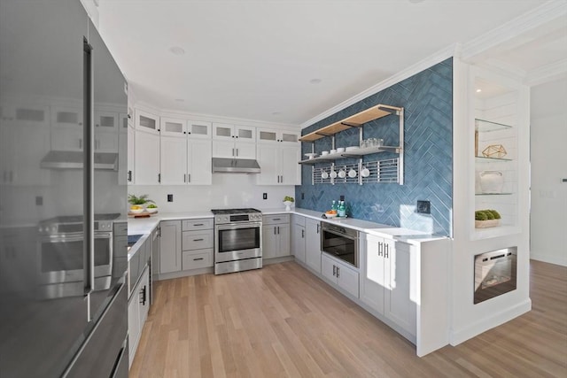 kitchen featuring light wood-style flooring, stainless steel range with gas cooktop, under cabinet range hood, and open shelves