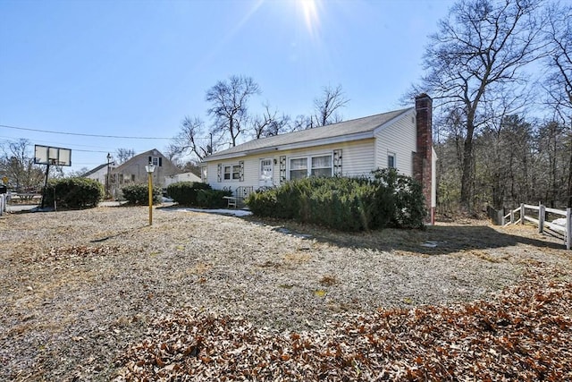 rear view of property featuring a chimney and fence