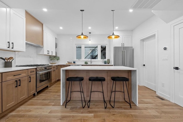 16 Edgar Ave, Somerville, MA 02145 - kitchen featuring premium appliances, a center island, a breakfast bar area, light wood-type flooring, and backsplash