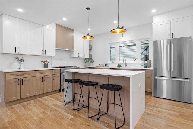 16 Edgar Ave, Somerville, MA 02145 - kitchen with stainless steel appliances, a sink, a kitchen bar, light wood-style flooring, and a kitchen island