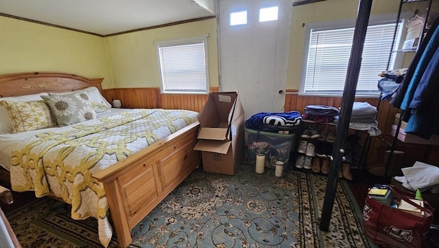 bedroom with ornamental molding and wood walls