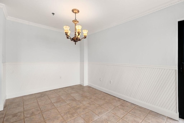 empty room with a chandelier, a wainscoted wall, crown molding, and baseboards