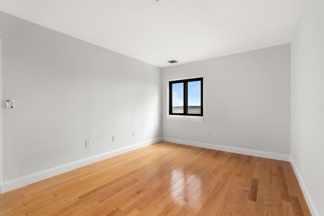 empty room featuring light wood-type flooring and baseboards