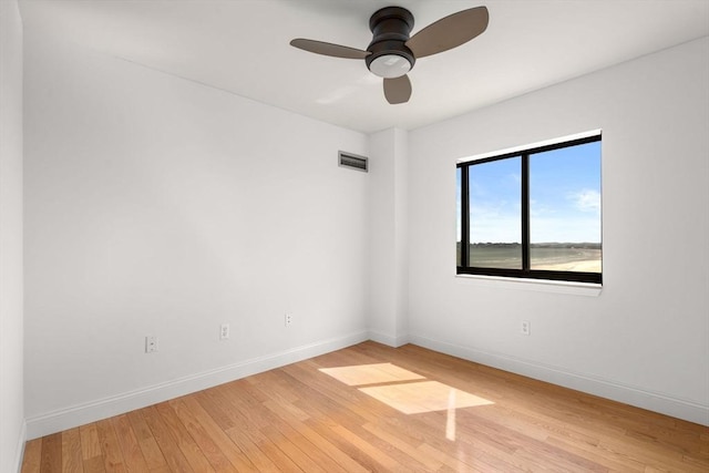 spare room featuring light wood-type flooring, baseboards, and a ceiling fan