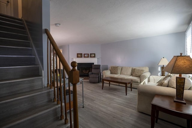 living area featuring wood finished floors, a fireplace, a textured ceiling, and stairs