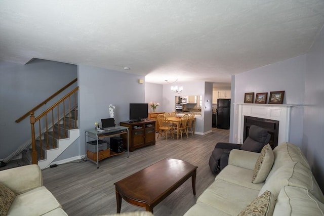 living area featuring stairs, baseboards, a fireplace, and wood finished floors