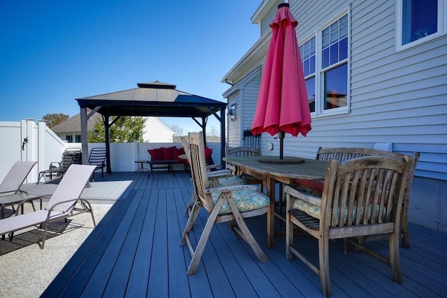 deck featuring a gazebo, outdoor dining area, and fence