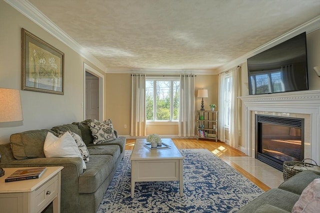 living area featuring crown molding, light wood finished floors, and a tile fireplace