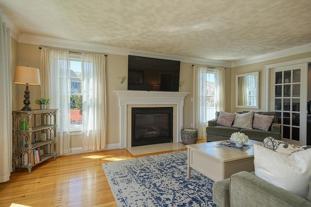 living area featuring a fireplace with flush hearth, baseboards, light wood finished floors, and a wealth of natural light