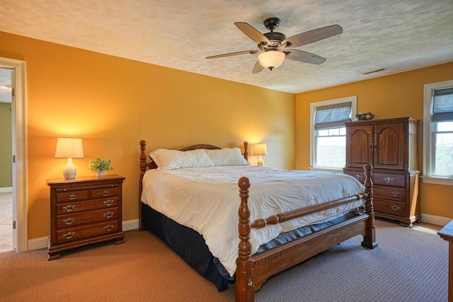 bedroom with visible vents, baseboards, ceiling fan, light colored carpet, and a textured ceiling