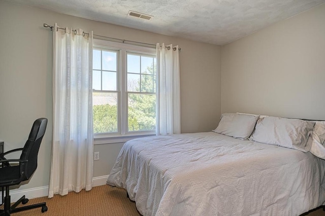 carpeted bedroom with visible vents, a textured ceiling, and baseboards