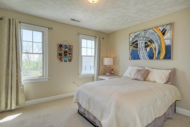 carpeted bedroom with baseboards, a textured ceiling, and visible vents