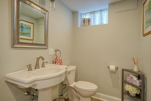 half bath featuring a sink, baseboards, and toilet