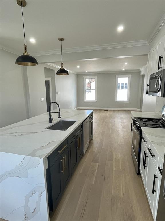 kitchen with a spacious island, white cabinetry, hanging light fixtures, and stainless steel appliances