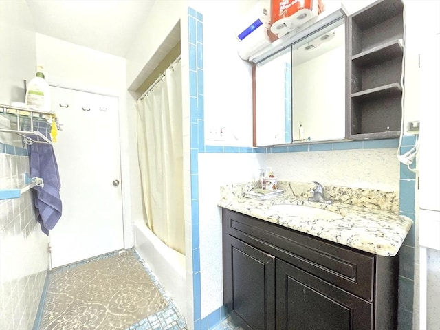 full bath with vanity, shower / bath combo, and tile walls