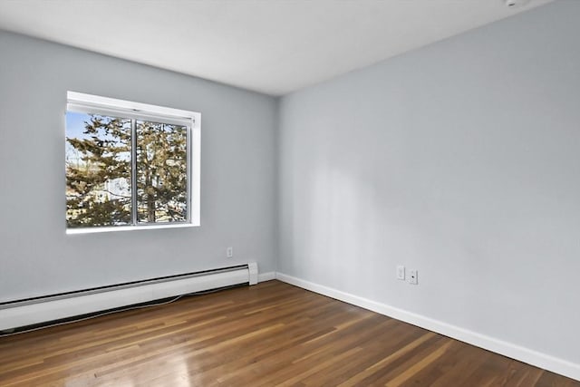 spare room featuring a baseboard radiator, baseboards, and wood finished floors