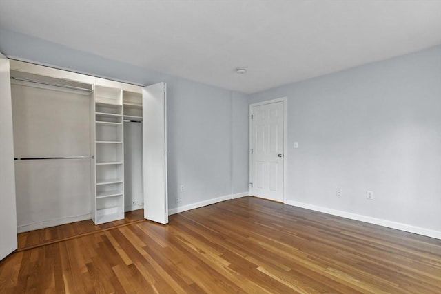 unfurnished bedroom with a closet, wood finished floors, and baseboards