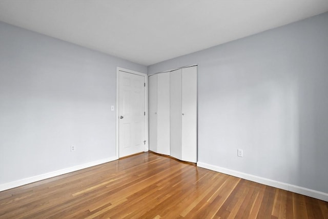 unfurnished bedroom featuring a closet, baseboards, and wood finished floors