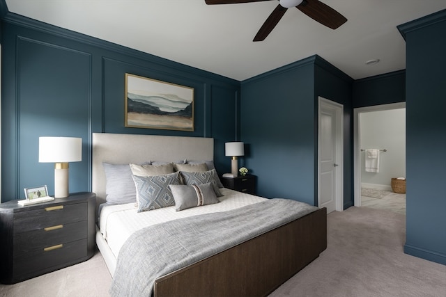 bedroom featuring ceiling fan, light colored carpet, ornamental molding, and ensuite bath