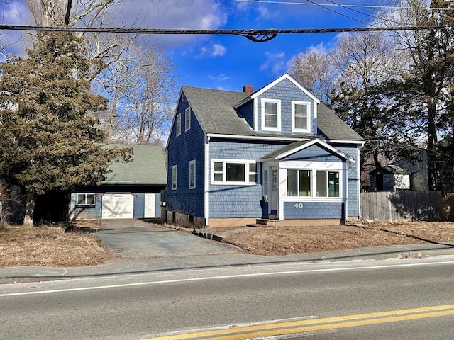 view of front of house with roof with shingles, a chimney, fence, and an outbuilding