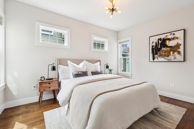 bedroom with baseboards, a chandelier, and wood finished floors