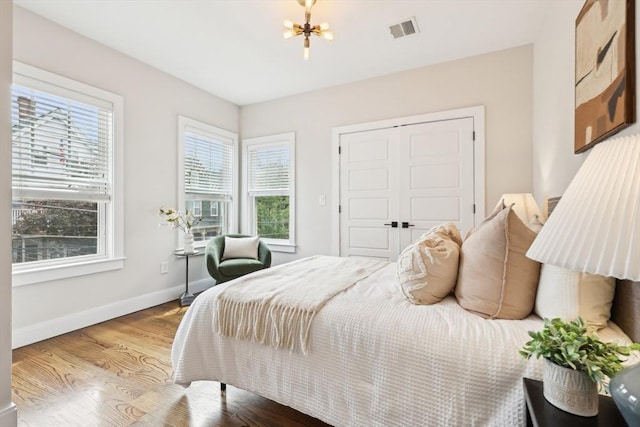 bedroom featuring wood finished floors, a chandelier, baseboards, and a closet