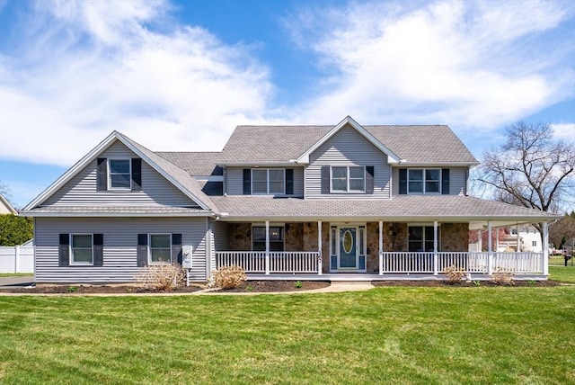 view of front of property featuring stone siding, a front yard, and covered porch