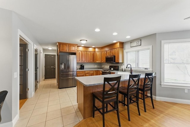 kitchen with recessed lighting, stainless steel appliances, a sink, baseboards, and a peninsula