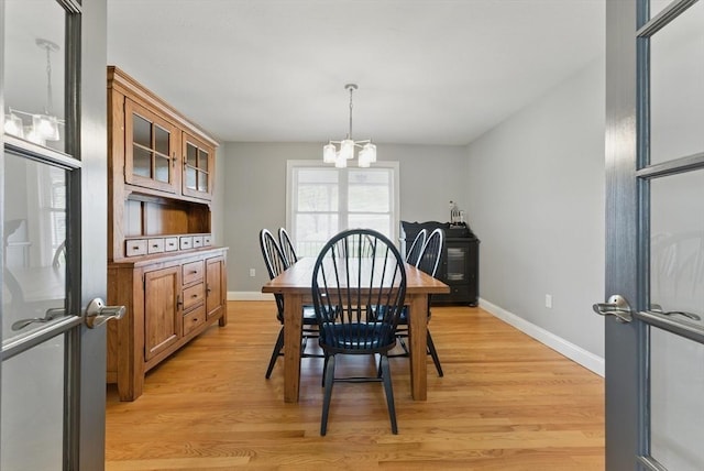 dining room featuring baseboards, a chandelier, and light wood finished floors