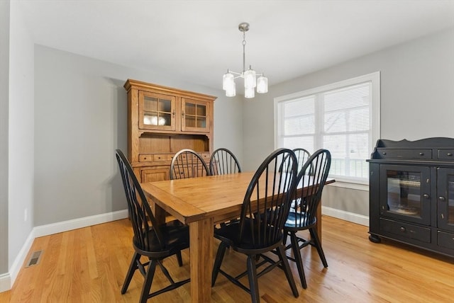 dining area with light wood-type flooring, baseboards, visible vents, and an inviting chandelier