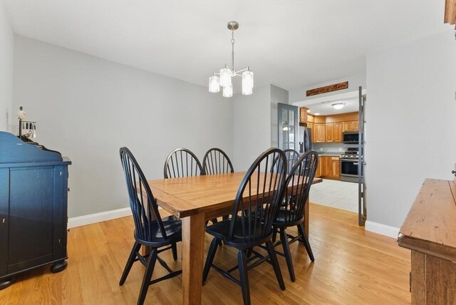 dining room featuring a chandelier, light wood finished floors, and baseboards
