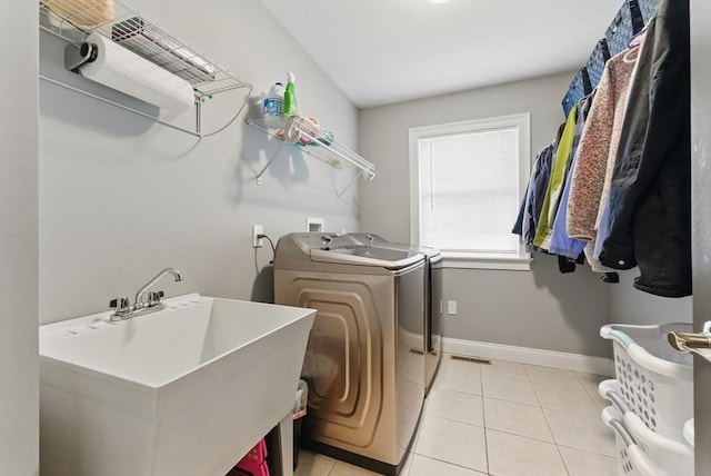 laundry area with washing machine and dryer, a sink, laundry area, and light tile patterned flooring