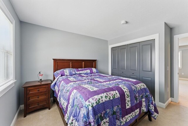 bedroom featuring baseboards, a closet, and light colored carpet