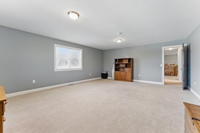 unfurnished living room featuring light carpet and baseboards