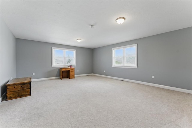 spare room featuring baseboards and light colored carpet