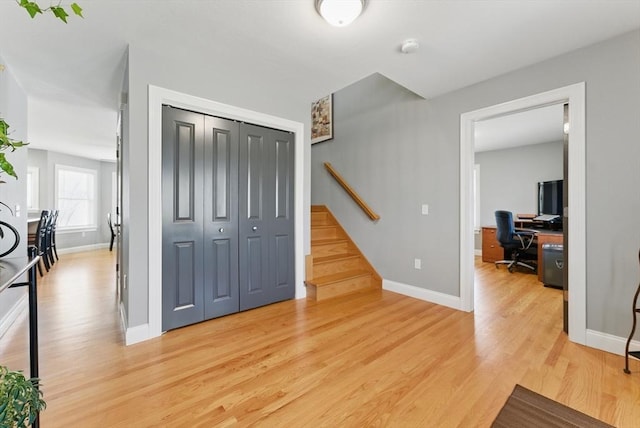foyer featuring baseboards, light wood-style floors, and stairs