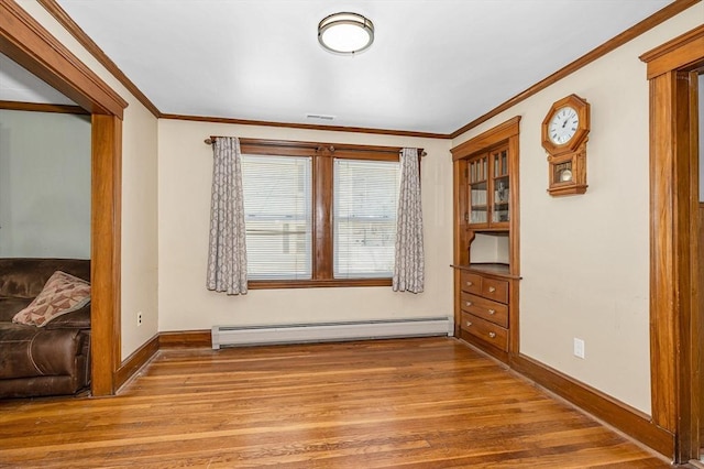 spare room with crown molding, a baseboard heating unit, baseboards, and wood finished floors