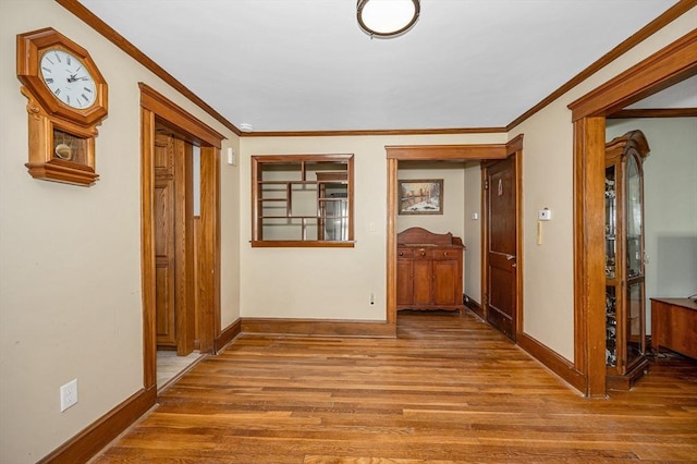 hall featuring crown molding, baseboards, and wood finished floors