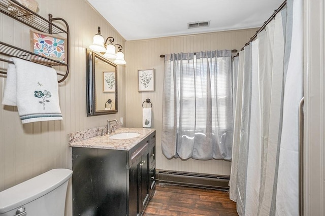 full bathroom featuring visible vents, a baseboard heating unit, toilet, hardwood / wood-style flooring, and vanity