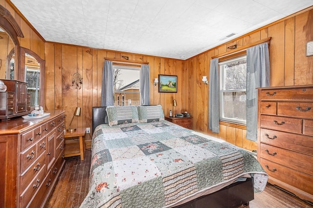 bedroom with visible vents, wood finished floors, and wood walls