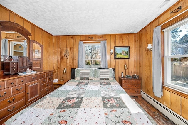 bedroom with baseboard heating, wooden walls, and wood finished floors