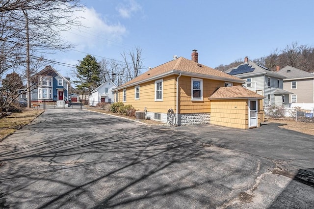 exterior space with driveway, a chimney, an outdoor structure, and fence