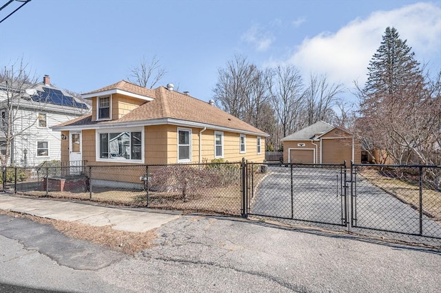 view of side of home with a gate, a fenced front yard, roof with shingles, an outdoor structure, and a garage